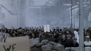 Movie still from “Bloody Sunday” (2002), directed by Paul Greengrass – A crowd of people sitting on top of rocks; Extreme Wide shot, High angle
