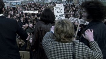 Movie still from “Bloody Sunday” (2002), directed by Paul Greengrass – A group of people protesting in front of a crowd of onlookers; Wide shot, High angle