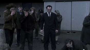 Movie still from “Bloody Sunday” (2002), directed by Paul Greengrass – A group of people standing in a parking lot; Wide shot, High angle