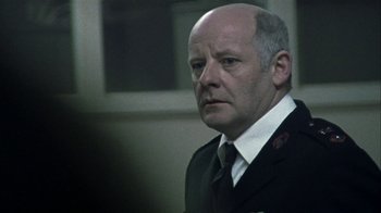 Movie still from “Bloody Sunday” (2002), directed by Paul Greengrass – An older man in a suit and tie looking at the camera; Close Up shot, Low angle