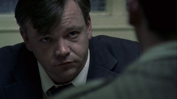 Movie still from “Bloody Sunday” (2002), directed by Paul Greengrass – A person wearing a suit and tie; Close Up shot, Over the shoulder angle