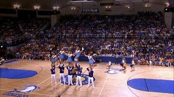 Movie still from “Blue Chips” (1994), directed by William Friedkin – A group of cheerleaders perform on a basketball court while a crowd watches; Extreme Wide shot, Overhead angle