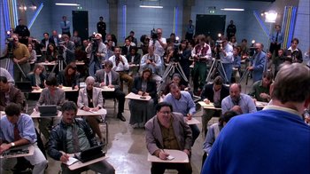 Movie still from “Blue Chips” (1994), directed by William Friedkin – A group of people sitting in a room with microphones; Wide shot, High angle