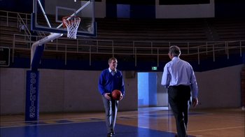 Movie still from “Blue Chips” (1994), directed by William Friedkin – Two men standing on a basketball court holding a basketball; Wide shot, Over the shoulder angle