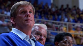 Movie still from “Blue Chips” (1994), directed by William Friedkin – A man in a blue shirt is watching a game; Close Up shot, Low angle