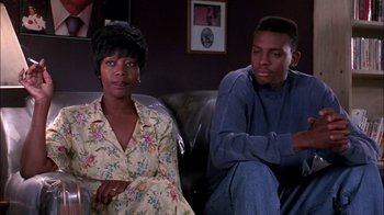 Movie still from “Blue Chips” (1994), directed by William Friedkin – A woman and a man sitting on a couch in a living room; Medium shot, Low angle