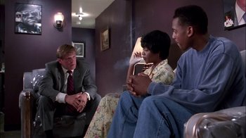 Movie still from “Blue Chips” (1994), directed by William Friedkin – A group of people sitting on a couch talking to each other; Medium shot, Low angle