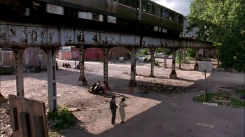 Movie still from “Blue Chips” (1994), directed by William Friedkin – Two people standing under an elevated train platform; Extreme Wide shot, High angle