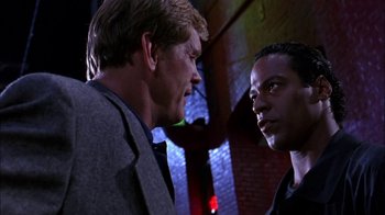 Movie still from “Blue Chips” (1994), directed by William Friedkin – Two men are facing each other in a dark room; Close Up shot, Low angle