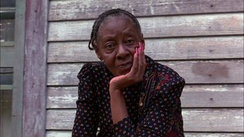 Movie still from “Blue Chips” (1994), directed by William Friedkin – An older woman is sitting against a wooden wall; Close Up shot, High angle