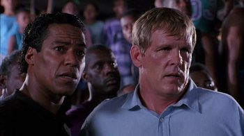 Movie still from “Blue Chips” (1994), directed by William Friedkin – Two men are standing in front of a group of people; Close Up shot, Low angle