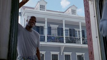 Movie still from “Blue Chips” (1994), directed by William Friedkin – A man standing in front of a large building; Medium shot, Low angle