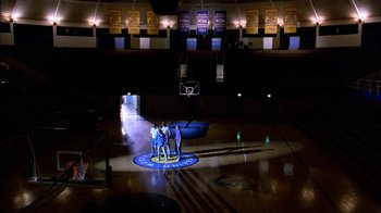 Movie still from “Blue Chips” (1994), directed by William Friedkin – A group of people standing on a basketball court in a gym; Extreme Wide shot, High angle