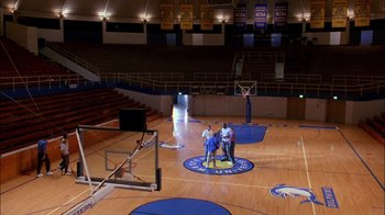 Movie still from “Blue Chips” (1994), directed by William Friedkin – Two men standing on a basketball court in an empty gym; Extreme Wide shot, High angle