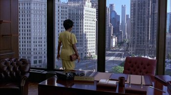 Movie still from “Blue Chips” (1994), directed by William Friedkin – A woman standing in front of a window looking out at a city; Extreme Wide shot, High angle