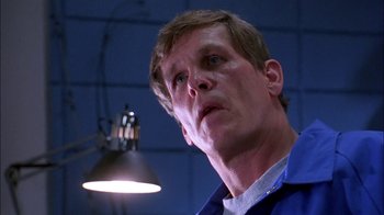 Movie still from “Blue Chips” (1994), directed by William Friedkin – A person wearing a blue shirt near a lamp; Close Up shot, Low angle
