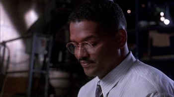 Movie still from “Blue Chips” (1994), directed by William Friedkin – A person wearing a suit and glasses; Close Up shot, Low angle