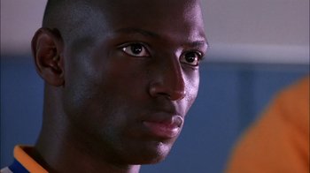 Movie still from “Blue Chips” (1994), directed by William Friedkin – A man's face in a dark room; Close Up shot, Low angle