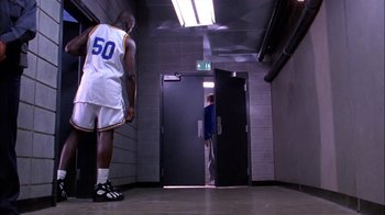 Movie still from “Blue Chips” (1994), directed by William Friedkin – Two basketball players are standing in a hallway; Wide shot, Low angle