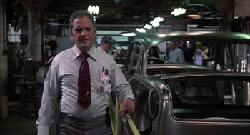 Movie still from “Blue Collar” (1978), directed by Paul Schrader – A man standing in front of cars in an assembly line; Medium shot, Low angle