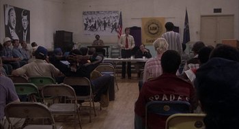Movie still from “Blue Collar” (1978), directed by Paul Schrader – A group of people sitting in chairs in a room; Wide shot, High angle