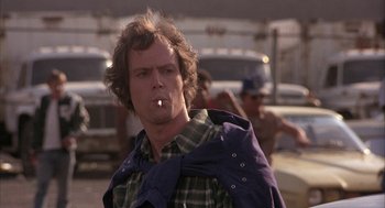 Movie still from “Blue Collar” (1978), directed by Paul Schrader – A man is smoking a cigarette while standing in a parking lot; Close Up shot, Low angle
