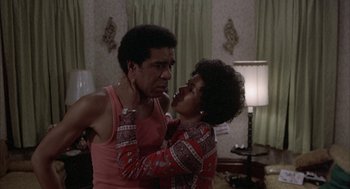 Movie still from “Blue Collar” (1978), directed by Paul Schrader – A man and a woman are hugging in a living room; Medium shot, Over the shoulder angle