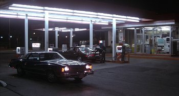 Movie still from “Blue Collar” (1978), directed by Paul Schrader – Cars are parked at a gas station at night; Extreme Wide shot, Low angle