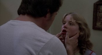 Movie still from “Blue Collar” (1978), directed by Paul Schrader – A man is putting lipstick on a woman's face; Close Up shot, Over the shoulder angle