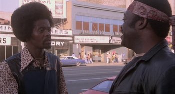 Movie still from “Blue Collar” (1978), directed by Paul Schrader – Two men standing on the side of the road talking to each other; Medium shot, Low angle