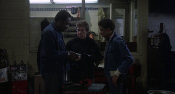 Movie still from “Blue Collar” (1978), directed by Paul Schrader – A group of men standing next to each other in a room; Medium shot, High angle