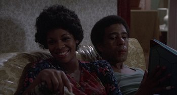 Movie still from “Blue Collar” (1978), directed by Paul Schrader – A woman and a man sitting on a couch together; Medium shot, High angle