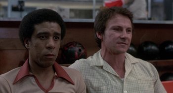 Movie still from “Blue Collar” (1978), directed by Paul Schrader – Two men standing next to each other in front of a bowling ball; Close Up shot, Low angle