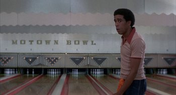 Movie still from “Blue Collar” (1978), directed by Paul Schrader – A man standing in front of a row of bowling pins; Medium shot, Low angle