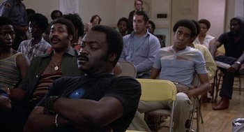 Movie still from “Blue Collar” (1978), directed by Paul Schrader – A group of people sitting in a room watching something; Medium shot, High angle