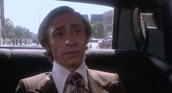 Movie still from “Blue Collar” (1978), directed by Paul Schrader – A man sitting in the back seat of a car wearing a suit; Close Up shot, High angle