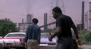 Movie still from “Blue Collar” (1978), directed by Paul Schrader – Two men standing next to each other on the side of the road; Medium shot, Over the shoulder angle