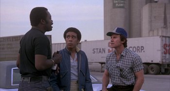 Movie still from “Blue Collar” (1978), directed by Paul Schrader – A group of men standing next to each other on a street; Medium shot, Low angle