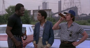 Movie still from “Blue Collar” (1978), directed by Paul Schrader – A group of men standing next to each other on the side of the road; Medium shot, Low angle