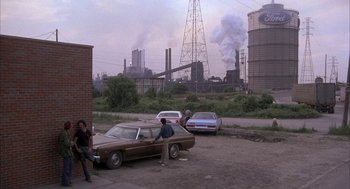 Movie still from “Blue Collar” (1978), directed by Paul Schrader – A couple of people sitting on top of a car; Wide shot, High angle