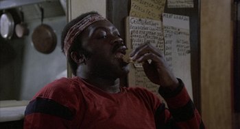 Movie still from “Blue Collar” (1978), directed by Paul Schrader – A man in a red shirt is eating a sandwich; Close Up shot, Over the shoulder angle