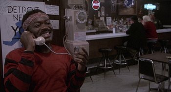 Movie still from “Blue Collar” (1978), directed by Paul Schrader – A man holding up a pay phone in front of a bar; Close Up shot, Low angle