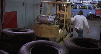 Movie still from “Blue Collar” (1978), directed by Paul Schrader – A man standing in front of a pile of tires; Wide shot, High angle