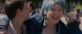 Movie still from “Blue Is the Warmest Colour” (2013), directed by Abdellatif Kechiche – Two women with blue hair smiling for the camera; Medium shot, Over the shoulder angle