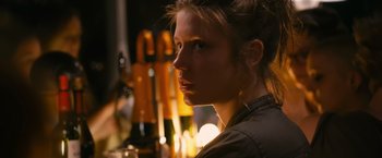 Movie still from “Blue Is the Warmest Colour” (2013), directed by Abdellatif Kechiche – A young woman is sitting in front of a bunch of wine bottles; Close Up shot, Low angle