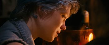 Movie still from “Blue Is the Warmest Colour” (2013), directed by Abdellatif Kechiche – A person's face in a dimly - lit room; Close Up shot, Over the shoulder angle