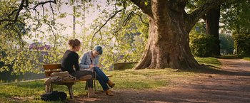 Movie still from “Blue Is the Warmest Colour” (2013), directed by Abdellatif Kechiche – Two women sitting on a bench under a large tree; Wide shot, Over the shoulder angle