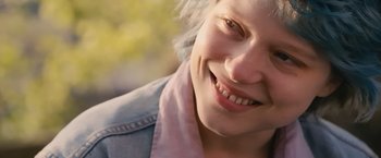 Movie still from “Blue Is the Warmest Colour” (2013), directed by Abdellatif Kechiche – A woman's face smiling; Close Up shot, Over the shoulder angle