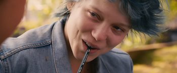 Movie still from “Blue Is the Warmest Colour” (2013), directed by Abdellatif Kechiche – A woman with blue hair is holding a pencil in her mouth; Close Up shot, High angle