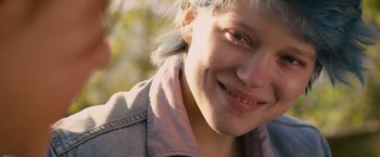 Movie still from “Blue Is the Warmest Colour” (2013), directed by Abdellatif Kechiche – A person with a jacket on smiling; Close Up shot, Over the shoulder angle